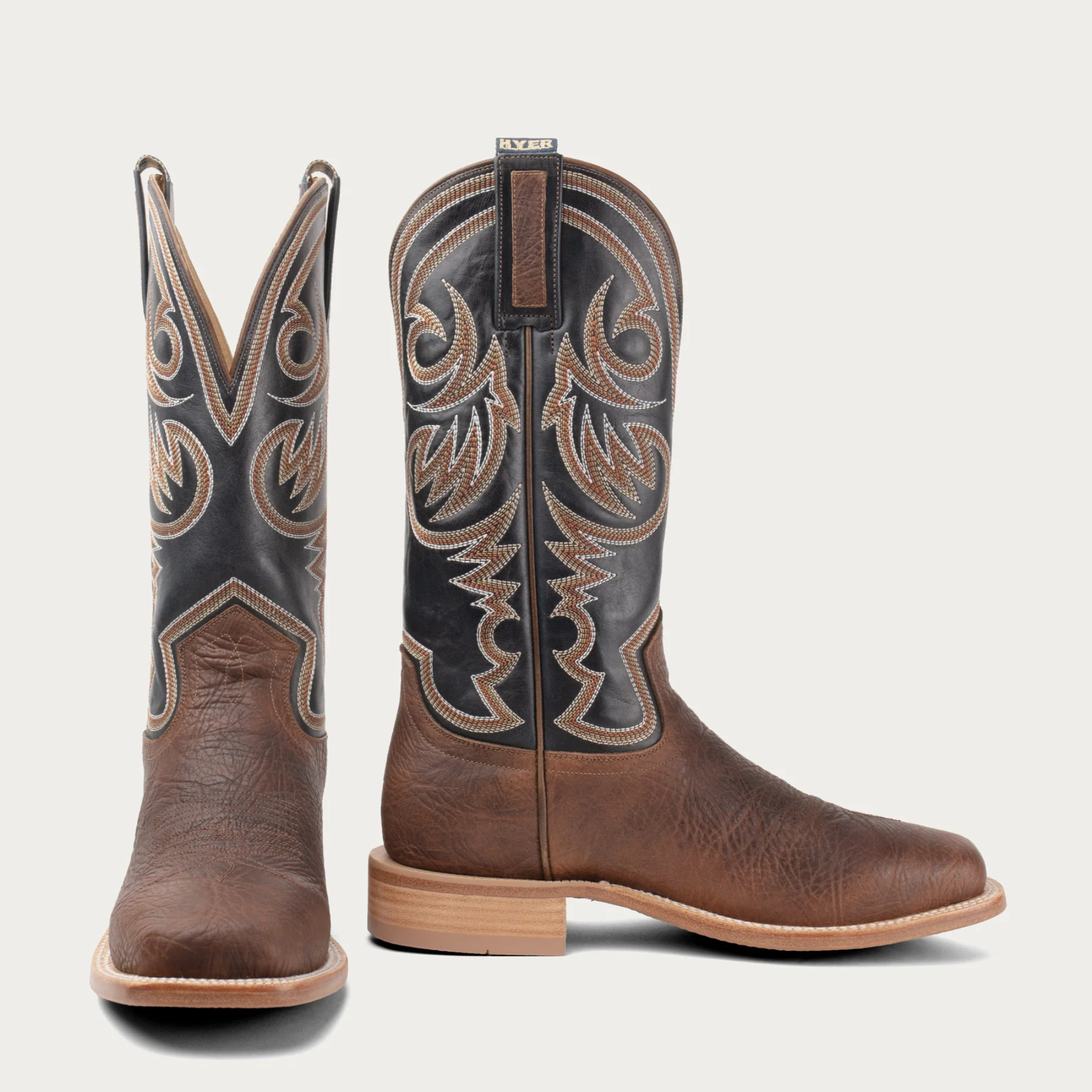 Pair of brown cowboy boots with intricate designs on a white background